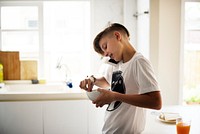 Closeup of young caucasain boy holding cereal bowl while talking on the phone in the kitchen