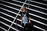 Young caucasian boy waking down the stairs with luggage