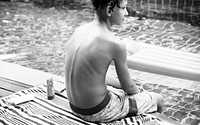 Teenage boy sitting near swimming pool