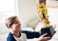 Young caucasian boy holding trophy cheerful happiness