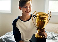 Young caucasian boy holding trophy cheerful happiness