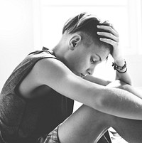 Closeup of young caucasian man sitting with face express of depressed upset emotion grayscale