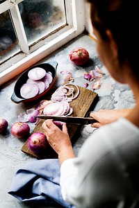 Closeup of hand with knife cutting slicing red onion