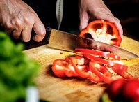 Closeup of hand with knife cutting bell pepper