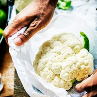 A person handling cauliflower