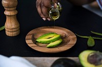 Closeup of fresh avocado on wooden plate topping with olive oil