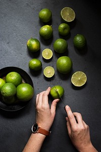 Hands cutting limes on black background