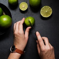 Hands cutting limes on black background