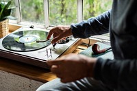 Hands insert vinyl disc to turntable player
