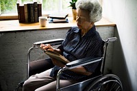 A woman sitting on a wheelchair reading a book