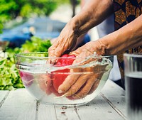 Hands cleaning a bell pepper in a glass bowl