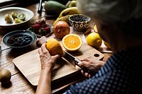 Senior woman cutting an orange