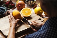 Closeup of hand with knife cutting orange