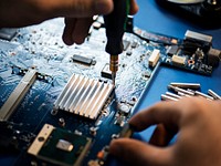 Closeup of hands with screwdriver over computer mainboard