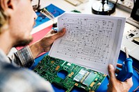 Technician studying electronics circuit guideline paper