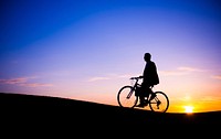 Businessman silhouette on a bike on the hill