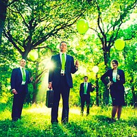 Group of business people holding balloons in the forest