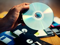 Hand holding CD disk background with floppy on the table