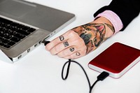 Hand with tattoo connect a external Hdd cable to laptop
