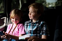 Young caucasian girl sitting inside car with brother