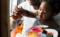 African descent dad teaching his child how to paint
