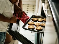 Black kid helping mom baking cookies in the kitchen