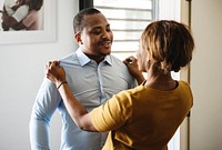 Black wife helping husband dress up for work