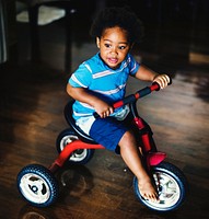 Black kid riding bicycle in the house