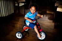 Black kid riding the bike in the house