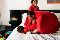 Black family playing together on bed