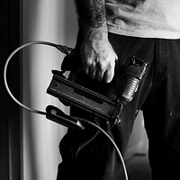 Hands with tattoo holding an equipment machine