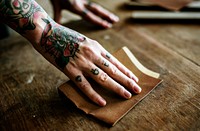 Hands with tattoo using sandpaper on a wood