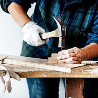 Woman carpenter using hammer pushing nail on a wood