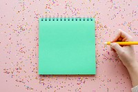 Blank notebook and pen with confetti