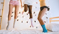 Group of diverse women jumping on bed together