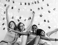 A group of diverse women sitting on bed together