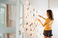 A young woman looking at photos hanging on decoration lights 