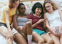 A group of diverse women lying on bed and using mobile phones
