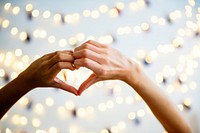 Heart shaped hands with decoration lights as a background