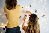 Women with photos hanging with decoration lights on the white wall