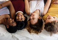Group of diverse women lying on bed together
