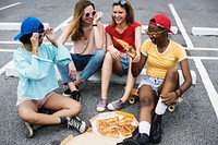 Diverse women sitting on floor eating pizza together