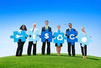 Group of Business People Holding Puzzle Pieces with Icons in an Open Field