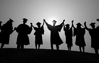 Silhouette of graduates raising their arms at sunset