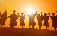 Silhouette of graduates raising their arms at sunset