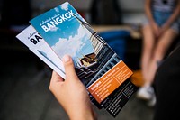 Closeup of hand holding Bangkok travel guide brochure