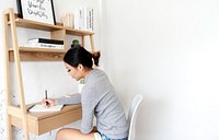 Asian woman sitting writing at the desk