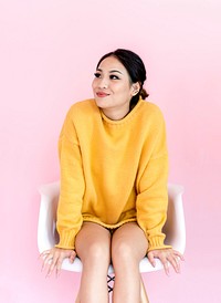 Asian woman sitting on white chair with pink background