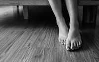 Closeup of woman legs on wooden floor grayscale