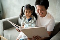 Asian father and daughter reading together